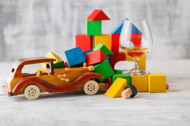Vintage wooden toy car with colorful blocks and a snifter glass of amber drink